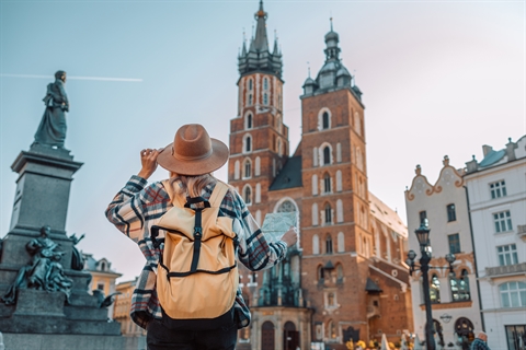 Back view of traveller woman walking on old Market Square in Krakow holding tourist map. Travel and active lifestyle concept. High quality photo Back view of traveller woman walking on old Market Square in Krakow holding tourist map. Travel and active lifestyle concept. High quality photo